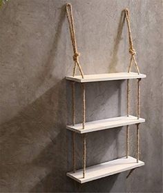 a white shelf with rope hanging from it's sides and two shelves on each side