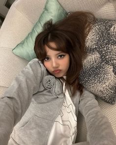 a young woman laying on top of a couch next to pillows