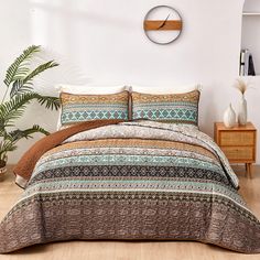 a bed covered in a brown and blue comforter next to a wooden dresser with a clock on the wall