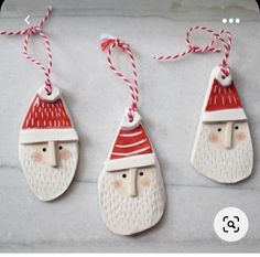 three christmas ornaments with santa hats and red noses hanging from twine on the wall