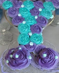 cupcakes with blue and purple frosting are arranged on a cake platter