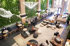 an overhead view of people sitting and standing in a lobby with plants on the wall