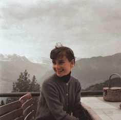 a woman sitting on top of a wooden bench