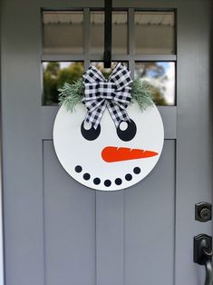 a snowman door hanger with a bow on it's head and nose