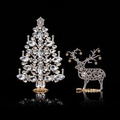 a crystal christmas tree next to an ornament shaped like a reindeer on a black background