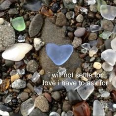 a heart shaped glass piece sitting on top of a pile of rocks and gravel with the words i will not seattle for love i have to ask for