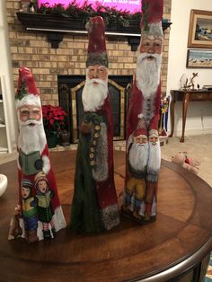 three gnome figurines sitting on top of a table in front of a fireplace