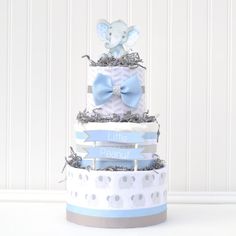 a three tiered baby shower cake with an elephant on top and blue ribbon around the edges