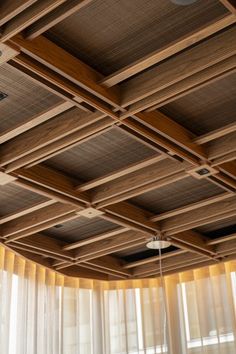 the ceiling is made of wood and has large windows with sheer drapes on them