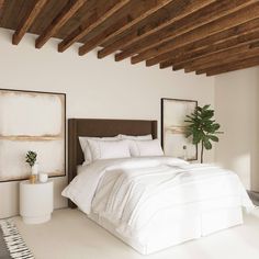 a bed with white sheets and pillows in a bedroom next to a potted plant