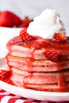 a stack of pancakes topped with whipped cream and strawberries