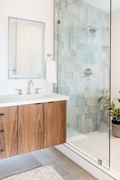 a bathroom with a glass shower door and wooden cabinetry, along with a rug on the floor