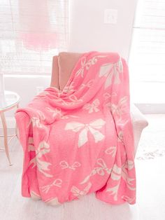 a pink blanket sitting on top of a white chair