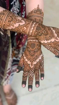 henna tattoos on the arms and hands of a woman with intricate designs, close up