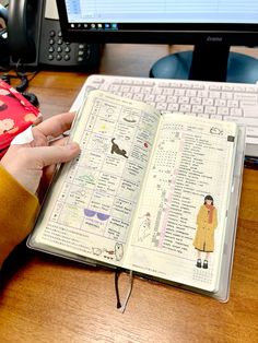 a person is holding an open book in front of a computer