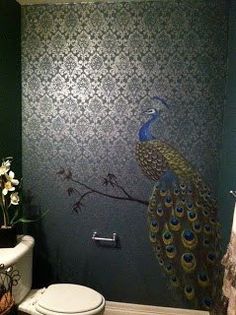 a peacock painted on the side of a wall next to a toilet in a bathroom