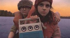 a man and woman sitting next to each other holding an old radio in front of them