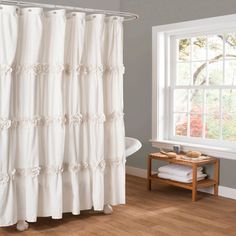 a white shower curtain with ruffles on it in front of a bathtub