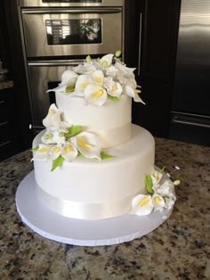 a three tiered cake with white flowers on it