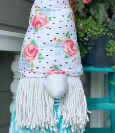 a white mannequin wearing a flowered hat with tassels