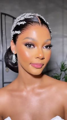 a woman in a wedding dress wearing a tiara and diamond earrings on her head