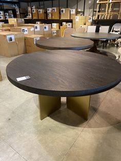 two circular tables in a warehouse with boxes on the floor and one table has an oval shaped top