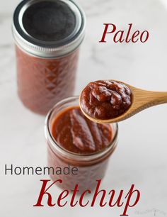 two jars filled with red sauce on top of a white counter next to a wooden spoon