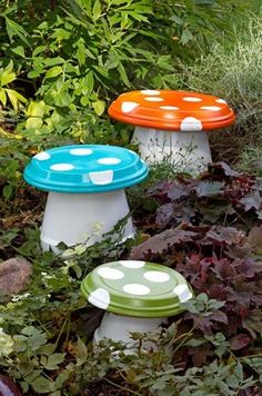 three different colored mushrooms sitting in the middle of some grass and flowers, one is white with dots on it