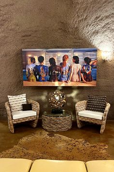 a living room with two chairs and a painting on the wall above it's couches