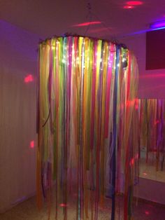 a room filled with lots of colorful streamers hanging from the ceiling next to a mirror