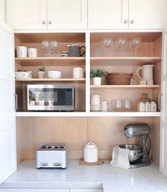 a kitchen with white cupboards filled with dishes and glasses on top of the counter