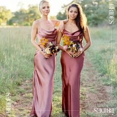 two women in long dresses standing next to each other on a dirt road with tall grass