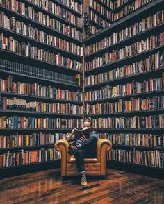 a man sitting on a chair in front of a bookshelf filled with lots of books