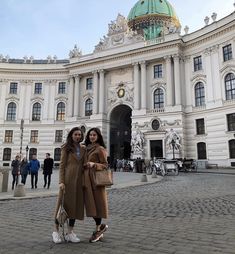 two women standing in front of a large building