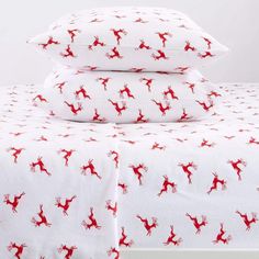 two pillows with red deers on them are stacked on top of each other in front of a white background