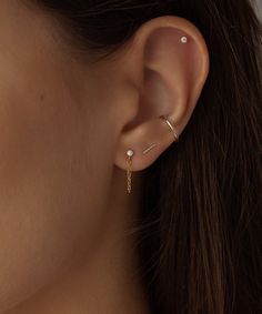 a woman's ear is shown with a gold chain attached to the side of her ear