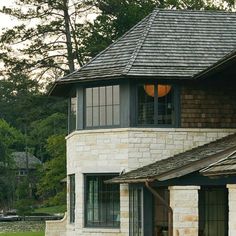 a brick house with an arched window and shingles on the roof is seen in this image