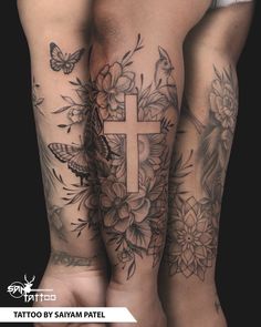 tattoos on both legs with flowers and a cross