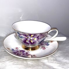 a cup and saucer with purple flowers on it