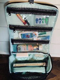 an open travel bag filled with toiletries and personal care items on top of a wooden floor