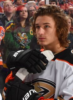 a hockey player is holding his gloves in front of the crowd