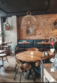 the interior of a restaurant with wooden tables, chairs and hanging lights above them is brick wall