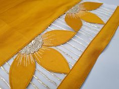 an orange and white dress with flower appliqued on the front, sitting on a table