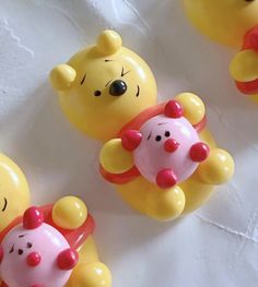 four winnie the pooh toys are lined up on a white tablecloth with red and yellow decorations