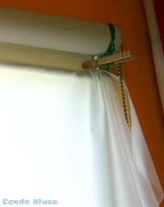 a white curtain is hanging on the side of a window with a wooden rod in front of it