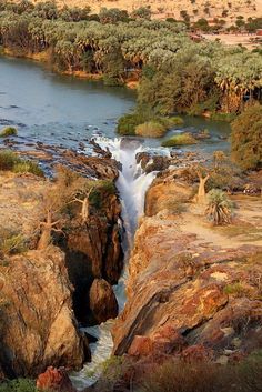 a river running through a lush green forest filled with lots of rocks and water flowing down it's sides