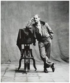 an old black and white photo of a man leaning on a chair