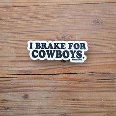 i brake for cowboys sticker sitting on top of a wooden table with the words, i brake for cowboys