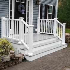 a porch with white railings and steps leading up to the front door on a blue house