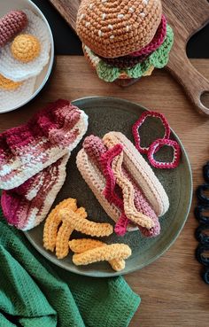 two crocheted hamburgers on a plate next to some scissors and other items